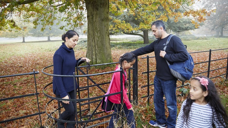 Family walking through a gate, on an autumn walk on the Osterley estate in London